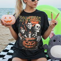 Person wearing a 'Halloween All Year Long' t-shirt on a beach with Halloween-themed items.