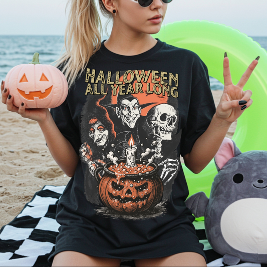 Person wearing a 'Halloween All Year Long' t-shirt on a beach with Halloween-themed items.